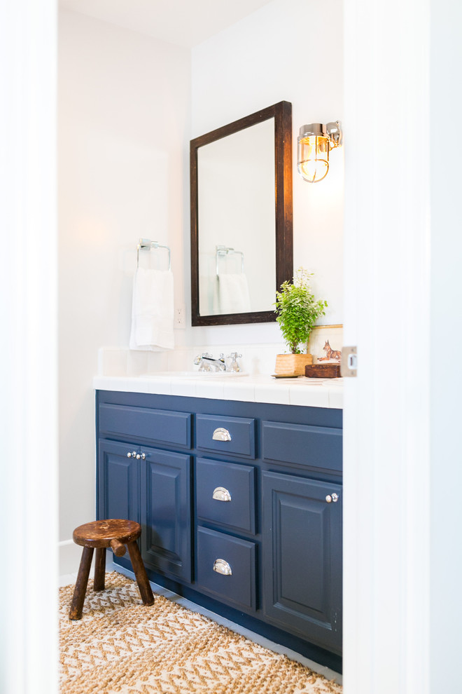 Beach style kids bathroom in Los Angeles with blue cabinets and white tile.
