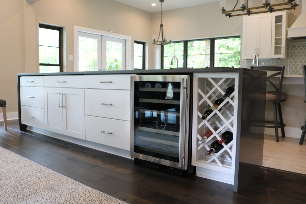 Inspiration for a transitional l-shaped porcelain tile and beige floor eat-in kitchen remodel in Austin with a farmhouse sink, shaker cabinets, white cabinets, quartzite countertops, gray backsplash, glass tile backsplash, stainless steel appliances, two islands and black countertops