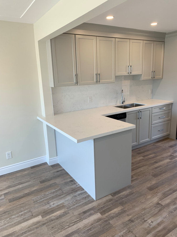 Example of a mid-sized transitional galley medium tone wood floor eat-in kitchen design with an undermount sink, shaker cabinets, gray cabinets, quartz countertops, white backsplash, quartz backsplash, stainless steel appliances, a peninsula and white countertops