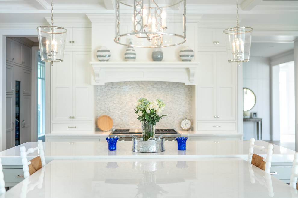 This is an example of a mid-sized beach style open plan kitchen in Other with beaded inset cabinets, white cabinets, marble benchtops, panelled appliances, light hardwood floors, with island, brown floor and white benchtop.