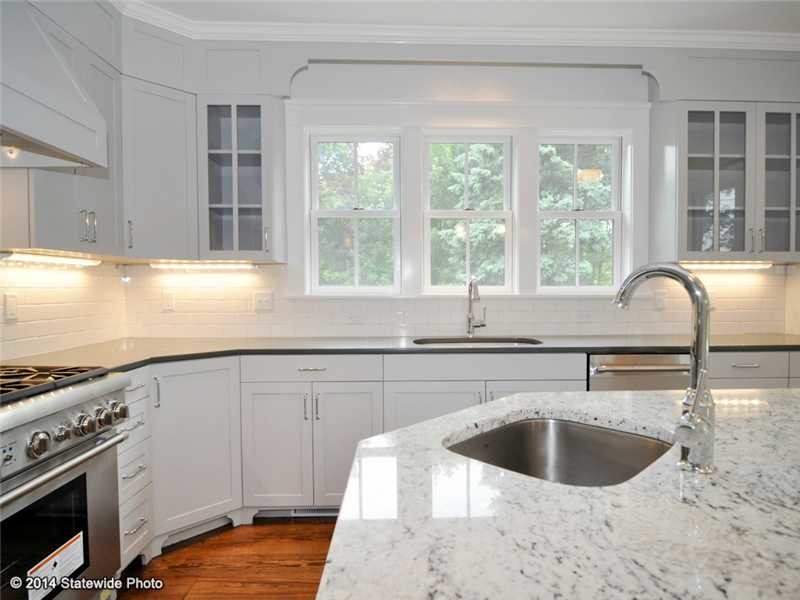 Kitchen - large transitional l-shaped medium tone wood floor kitchen idea in Providence with an undermount sink, shaker cabinets, white cabinets, granite countertops, white backsplash, stainless steel appliances, an island and subway tile backsplash