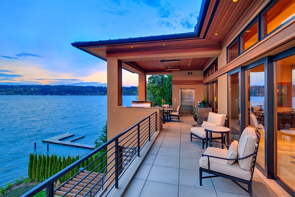 This is an example of a contemporary deck in Seattle with a fire feature and a roof extension.