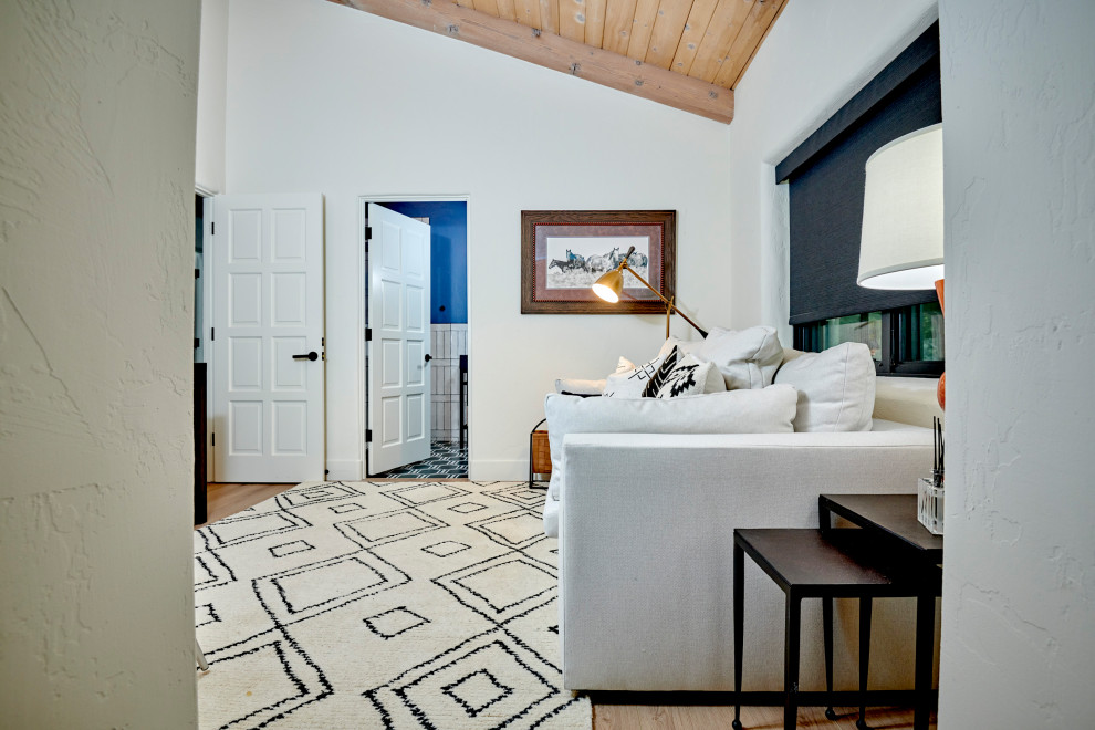 Modelo de habitación de invitados tradicional renovada de tamaño medio con paredes blancas, suelo de madera en tonos medios, suelo marrón y vigas vistas