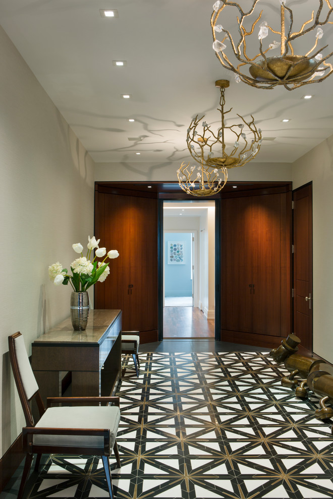 This is an example of an expansive contemporary foyer in New York with beige walls, marble floors, a single front door, a dark wood front door and black floor.