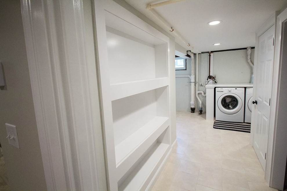 Mid-sized traditional single-wall utility room in Boston with open cabinets, white cabinets, solid surface benchtops, beige walls, ceramic floors and a side-by-side washer and dryer.
