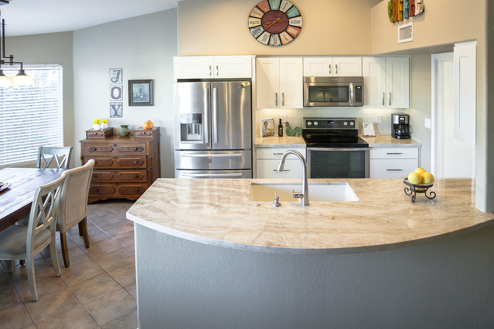 Transitional galley ceramic tile open concept kitchen photo in Phoenix with an undermount sink, recessed-panel cabinets, white cabinets, quartz countertops, white backsplash, ceramic backsplash, stainless steel appliances and an island