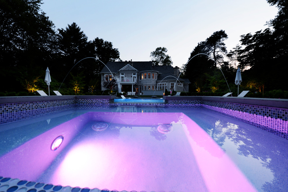 Design ideas for a modern backyard rectangular pool in New York with a water feature and concrete pavers.
