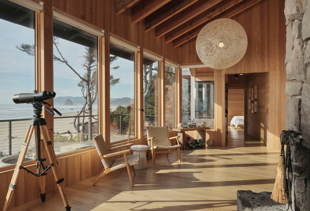 Mid-sized beach style open concept medium tone wood floor, brown floor, vaulted ceiling and wood wall living room photo in Milwaukee with brown walls, a standard fireplace and a stone fireplace