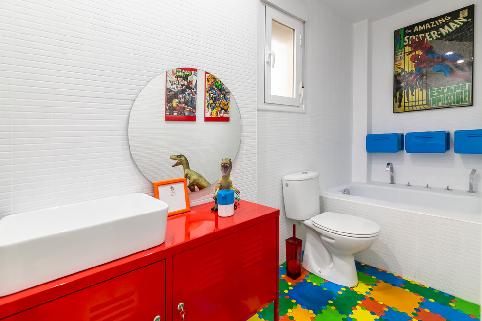 Photo of a contemporary kids bathroom in Other with red cabinets, an alcove tub, a two-piece toilet, white tile, white walls, a vessel sink, multi-coloured floor, red benchtops and flat-panel cabinets.