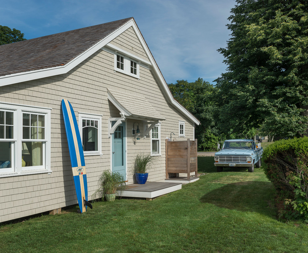 Photo of a beach style two-storey beige exterior in Providence with wood siding.