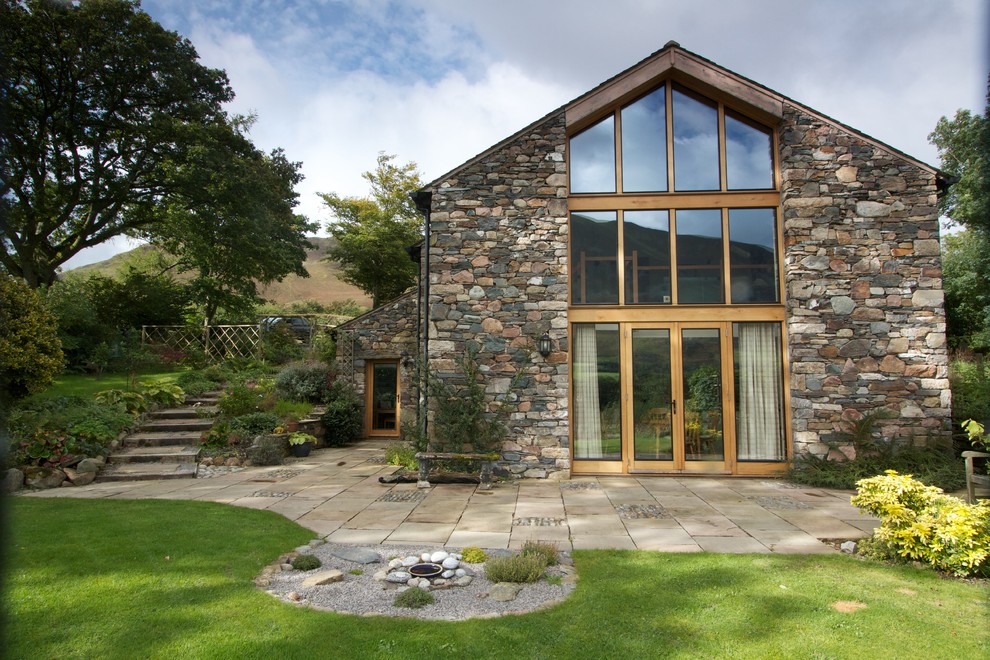 Large country grey exterior in Other with stone veneer and a gable roof.