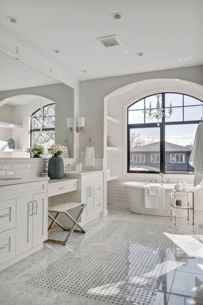 Expansive transitional master bathroom in Calgary with shaker cabinets, white cabinets, a freestanding tub, white tile, subway tile, grey walls, an undermount sink, grey floor, white benchtops, a double vanity and a built-in vanity.