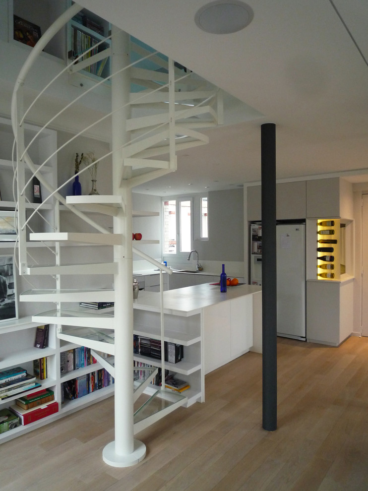 Contemporary glass spiral staircase in Paris with open risers and metal railing.