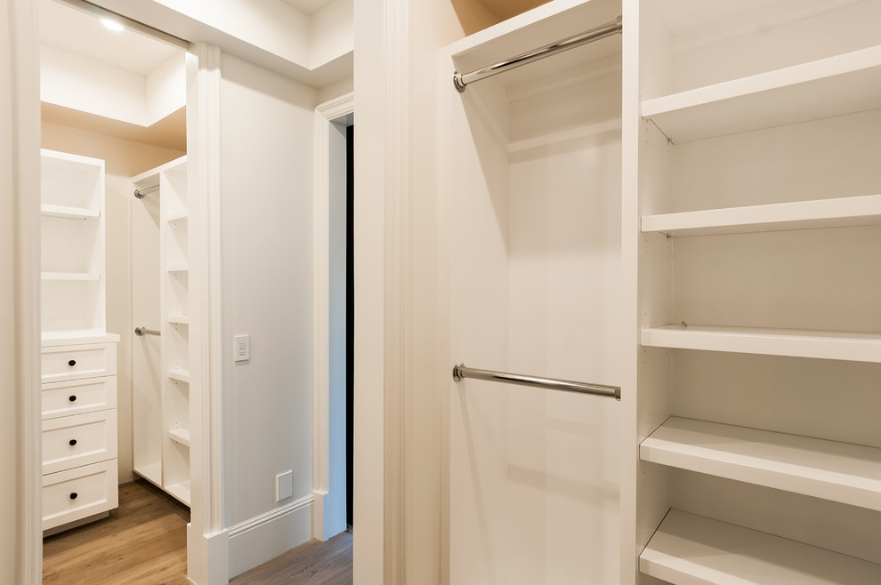 Inspiration for a mid-sized contemporary gender-neutral walk-in wardrobe in Los Angeles with recessed-panel cabinets, white cabinets, light hardwood floors and brown floor.
