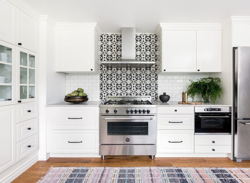 Mid-sized eclectic single-wall separate kitchen in Seattle with raised-panel cabinets, white cabinets, marble benchtops, multi-coloured splashback, ceramic splashback, stainless steel appliances, medium hardwood floors, no island and brown floor.