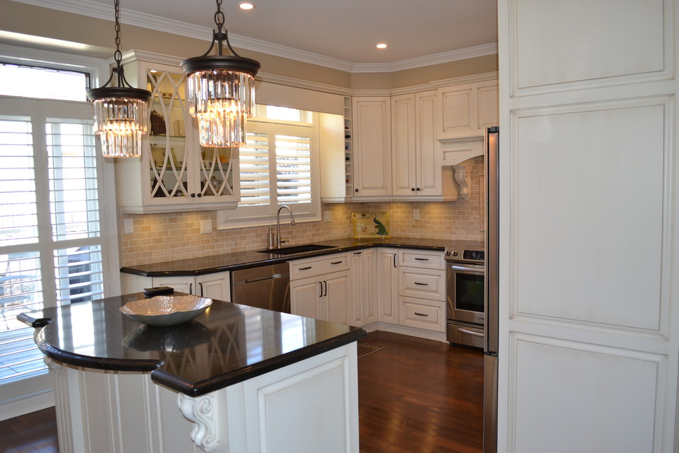 Eat-in kitchen - mid-sized transitional galley dark wood floor eat-in kitchen idea in Toronto with a drop-in sink, raised-panel cabinets, beige cabinets, quartz countertops, beige backsplash, stone tile backsplash, stainless steel appliances and an island