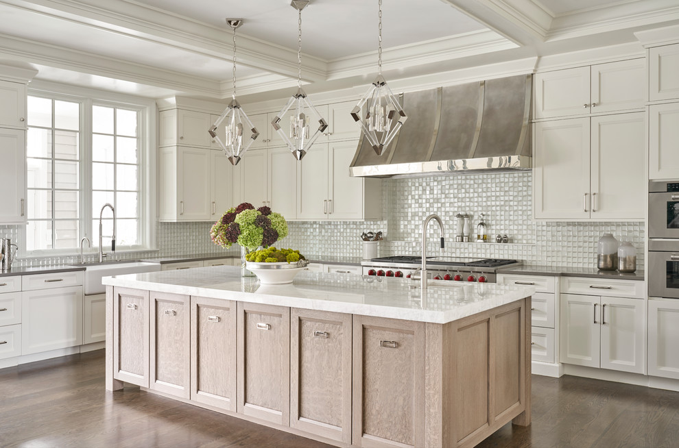 Inspiration for a transitional l-shaped kitchen in Chicago with a farmhouse sink, recessed-panel cabinets, white cabinets, white splashback, stainless steel appliances, dark hardwood floors, with island, brown floor and grey benchtop.