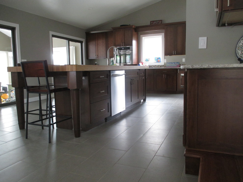 Example of a transitional galley ceramic tile eat-in kitchen design with a drop-in sink, shaker cabinets, dark wood cabinets, quartz countertops, multicolored backsplash, glass tile backsplash, stainless steel appliances and an island