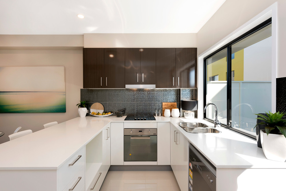 This is an example of a small modern u-shaped open plan kitchen in Brisbane with a double-bowl sink, flat-panel cabinets, quartz benchtops, metallic splashback, stainless steel appliances, porcelain floors, a peninsula, white cabinets and ceramic splashback.