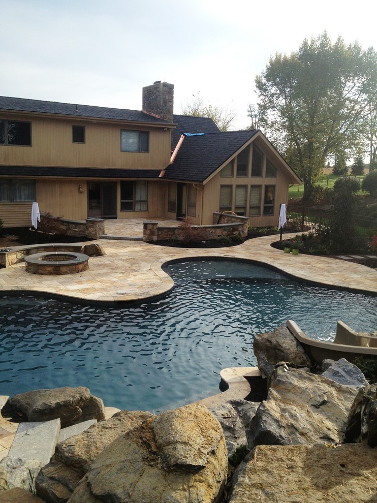 Design ideas for a large traditional backyard custom-shaped natural pool in Philadelphia with a water slide and natural stone pavers.