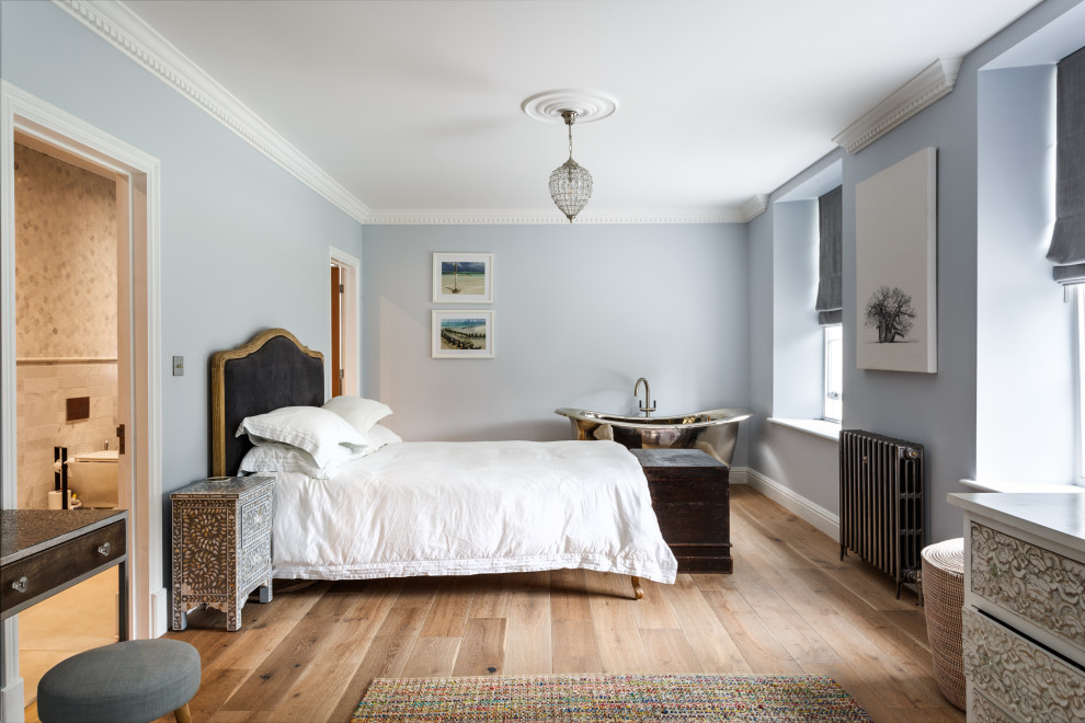 Ejemplo de dormitorio principal tradicional grande con paredes azules, suelo de madera clara y suelo naranja