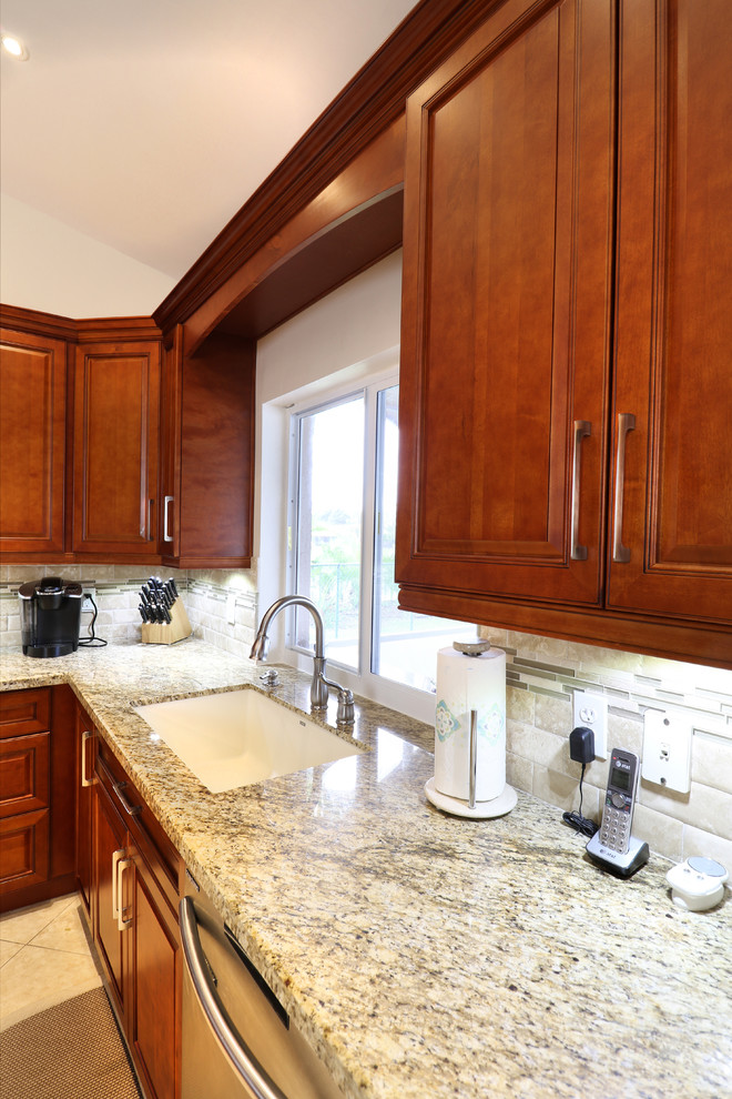 Example of a mid-sized transitional u-shaped porcelain tile eat-in kitchen design in Miami with an undermount sink, raised-panel cabinets, medium tone wood cabinets, granite countertops, beige backsplash, mosaic tile backsplash, stainless steel appliances and no island