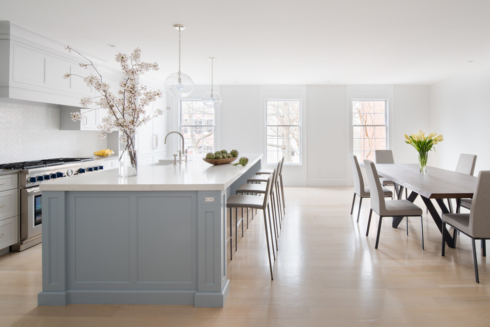 Example of a large transitional single-wall laminate floor and beige floor eat-in kitchen design in DC Metro with a farmhouse sink, flat-panel cabinets, blue cabinets, quartz countertops, white backsplash, mosaic tile backsplash, stainless steel appliances, an island and gray countertops