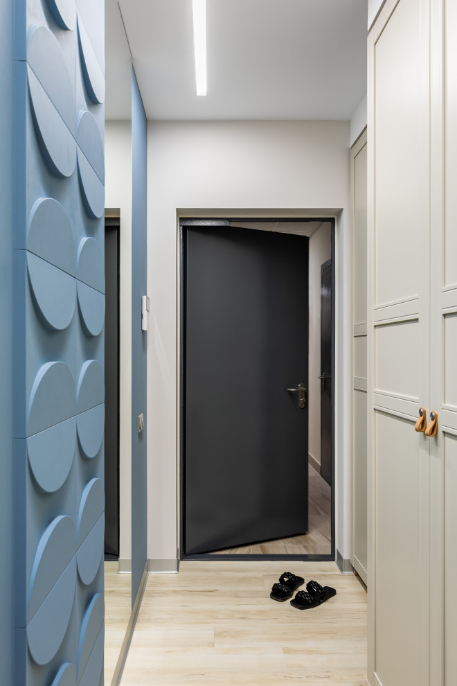 Cette image montre un petit couloir avec un mur gris, un sol en bois brun et un sol beige.