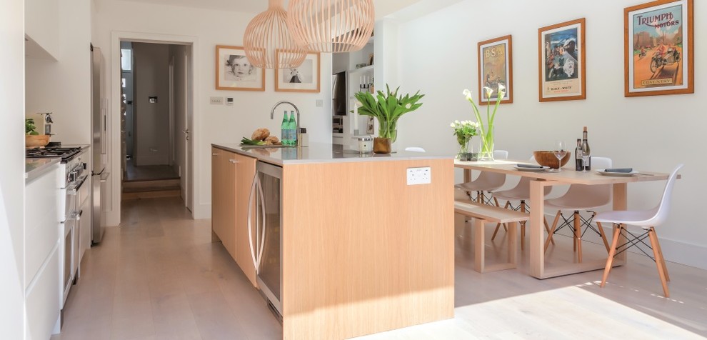 Photo of a mid-sized scandinavian single-wall eat-in kitchen in London with an integrated sink, louvered cabinets, white cabinets, solid surface benchtops, pink splashback, ceramic splashback, stainless steel appliances, linoleum floors, with island and white floor.