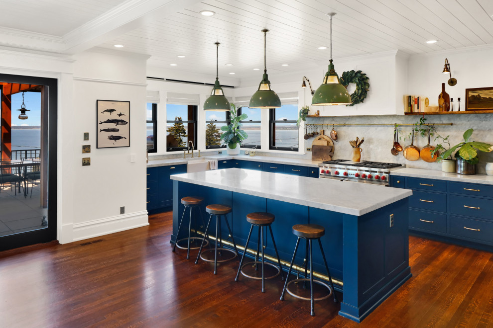 Foto på ett stort amerikanskt vit kök, med en enkel diskho, släta luckor, blå skåp, marmorbänkskiva, grått stänkskydd, stänkskydd i marmor, rostfria vitvaror, ljust trägolv, en köksö och orange golv