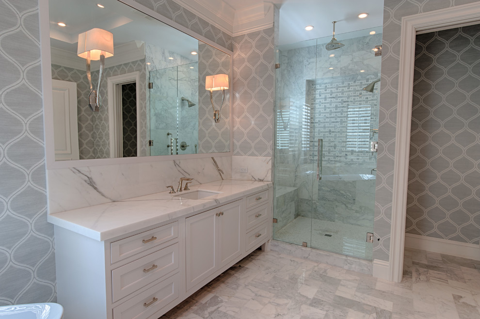 Large transitional master bathroom in Miami with shaker cabinets, white cabinets, a freestanding tub, an alcove shower, gray tile, white tile, stone slab, grey walls, marble floors, an undermount sink, marble benchtops, grey floor and a hinged shower door.