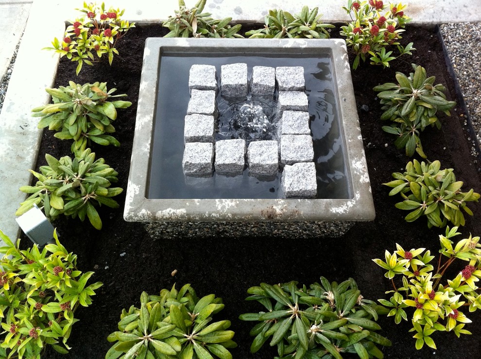 Small contemporary sloped partial sun garden in Vancouver with a water feature and gravel for spring.