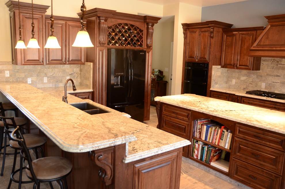 This is an example of a traditional galley eat-in kitchen in Other with an undermount sink, beaded inset cabinets, medium wood cabinets, granite benchtops, beige splashback, black appliances, travertine floors and with island.