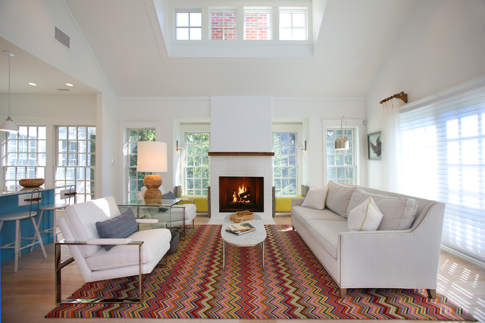 This is an example of a large beach style open concept living room in Philadelphia with white walls, light hardwood floors, a standard fireplace and a brick fireplace surround.