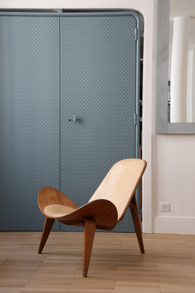 Ejemplo de armario y vestidor unisex industrial con a medida, armarios con rebordes decorativos, puertas de armario azules y suelo de madera clara