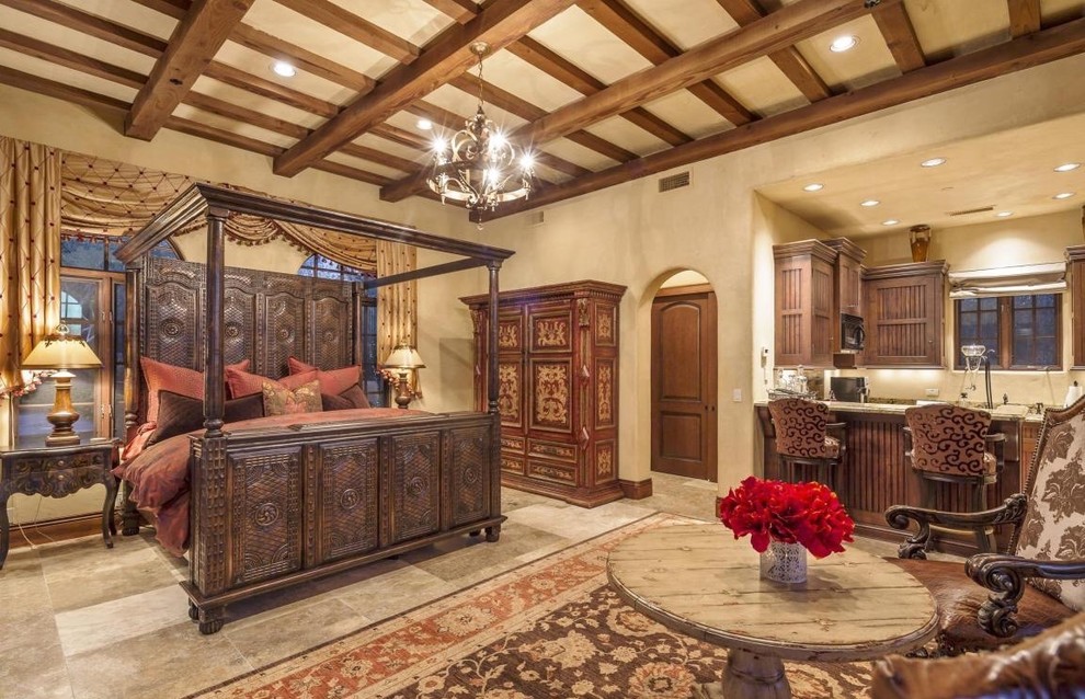 This is an example of a large mediterranean guest bedroom in Phoenix with beige walls, ceramic floors, a standard fireplace and a stone fireplace surround.
