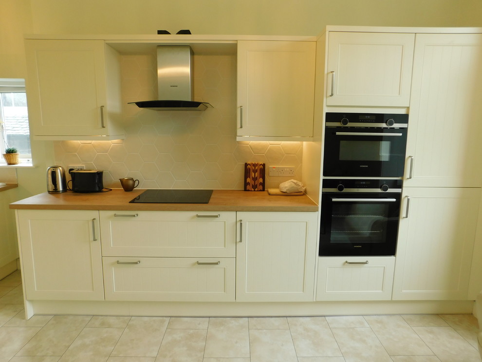 Photo of a mid-sized traditional l-shaped eat-in kitchen in Edinburgh with flat-panel cabinets, laminate benchtops, porcelain splashback, black appliances, vinyl floors and no island.