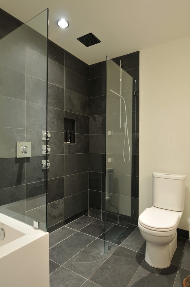 Design ideas for a mid-sized contemporary bathroom in Vancouver with a vessel sink, flat-panel cabinets, light wood cabinets, engineered quartz benchtops, a drop-in tub, a corner shower, a two-piece toilet, black tile, stone tile, white walls and slate floors.