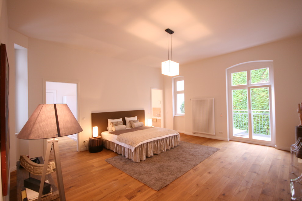 Inspiration for an expansive eclectic master bedroom in Berlin with white walls, medium hardwood floors and no fireplace.