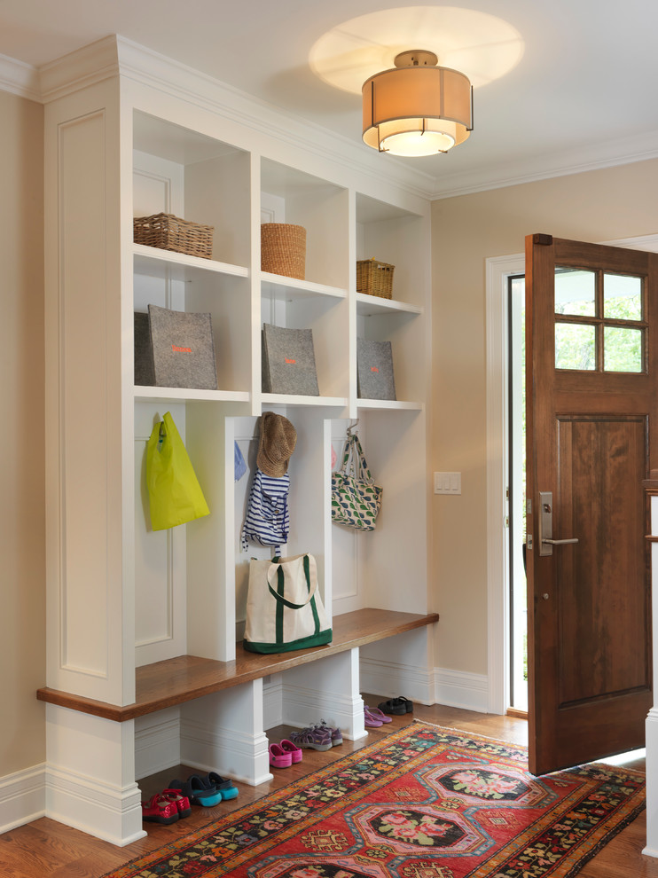 This is an example of a country mudroom in Providence with beige walls, medium hardwood floors, a single front door and a medium wood front door.