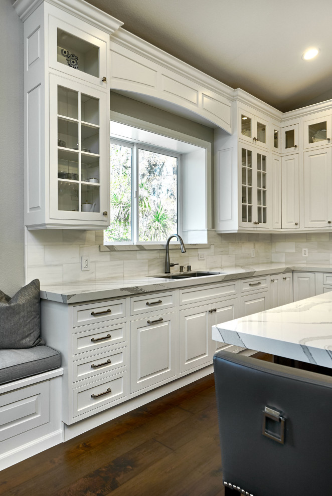 Idéer för ett stort klassiskt grå kök, med en undermonterad diskho, luckor med profilerade fronter, vita skåp, bänkskiva i kvarts, vitt stänkskydd, stänkskydd i marmor, rostfria vitvaror, mörkt trägolv, en köksö och brunt golv