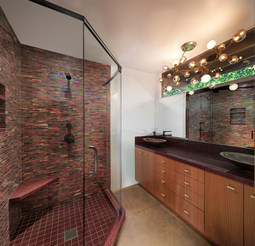 Photo of a mid-sized midcentury master bathroom in Los Angeles with flat-panel cabinets, medium wood cabinets, a corner shower, a two-piece toilet, red tile, glass tile, white walls, concrete floors and a vessel sink.