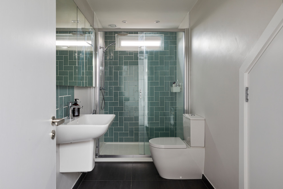 Пример оригинального дизайна: маленькая ванная комната в стиле модернизм с плоскими фасадами, душем без бортиков, раздельным унитазом, зеленой плиткой, белыми стенами, полом из керамогранита, душевой кабиной, подвесной раковиной, черным полом, душем с раздвижными дверями, тумбой под одну раковину и встроенной тумбой для на участке и в саду