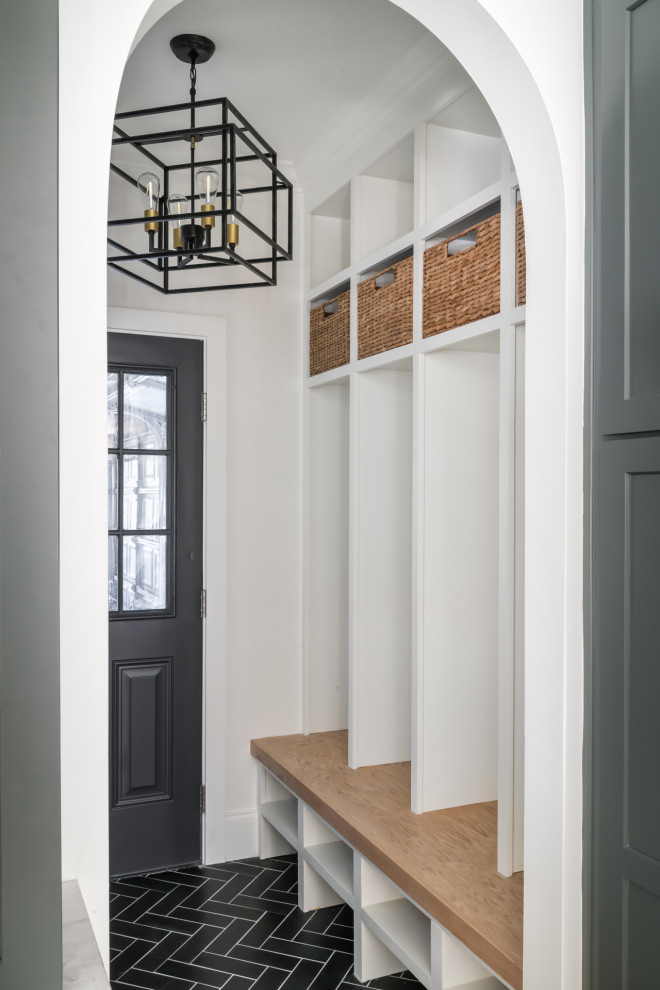 This is an example of a medium sized classic boot room in Atlanta with white walls, ceramic flooring, a single front door, a black front door and black floors.