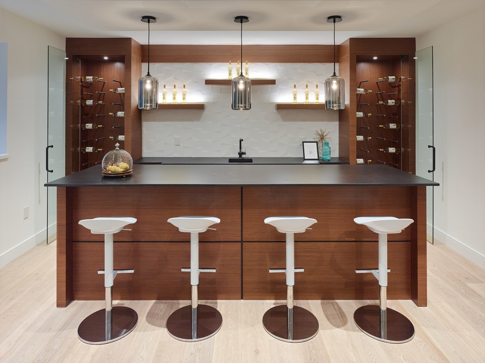 Design ideas for a contemporary seated home bar in Vancouver with open cabinets, medium wood cabinets, white splashback, light hardwood floors and black benchtop.