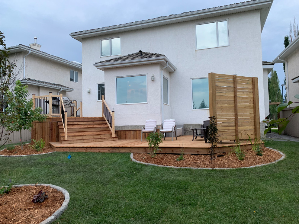 Large backyard privacy and mixed material railing deck photo in Edmonton