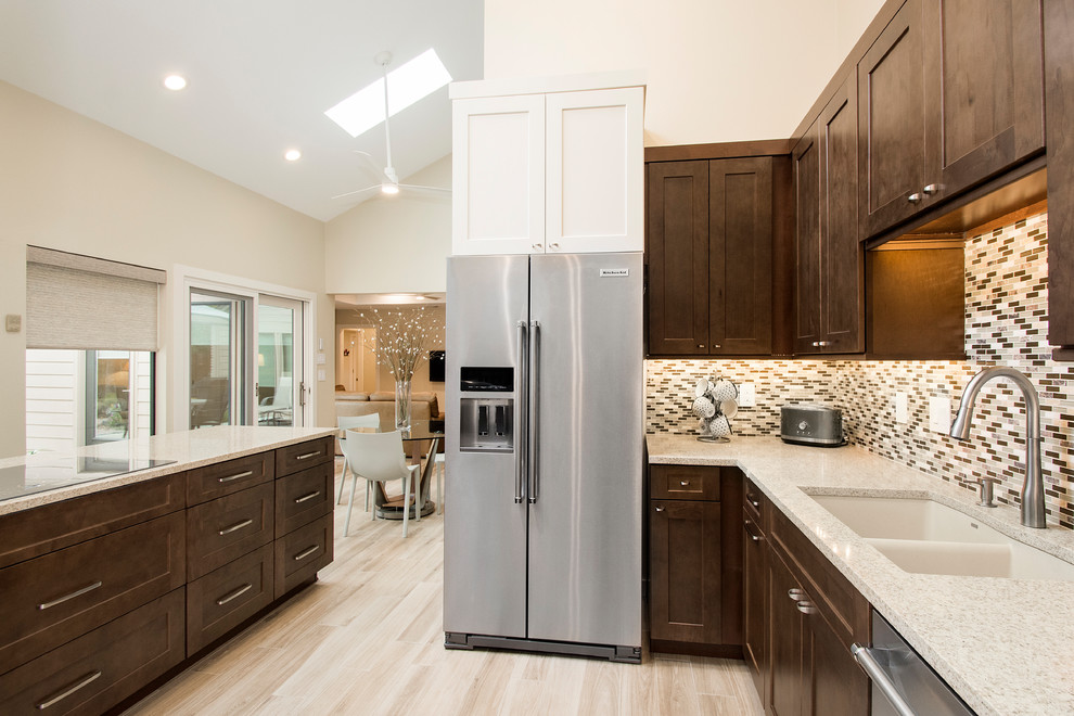This is an example of a large arts and crafts l-shaped separate kitchen in Dallas with light hardwood floors, beige floor, an undermount sink, flat-panel cabinets, dark wood cabinets, quartz benchtops, brown splashback, glass tile splashback, stainless steel appliances and a peninsula.