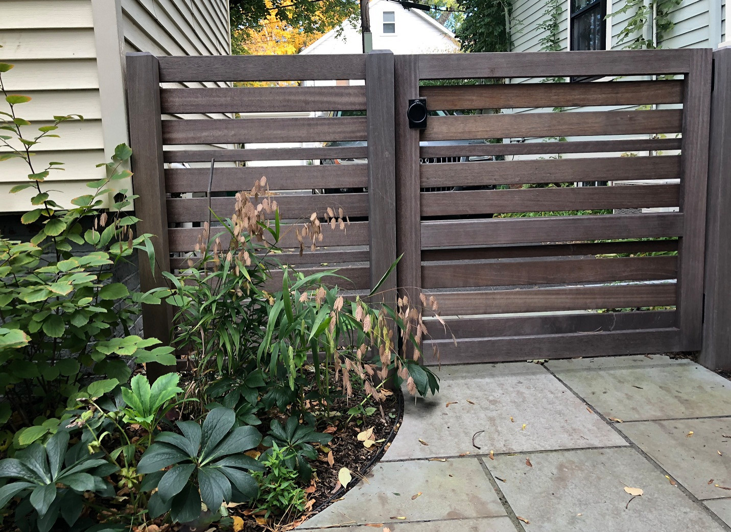 Mahogany garden gate separates driveway from garden