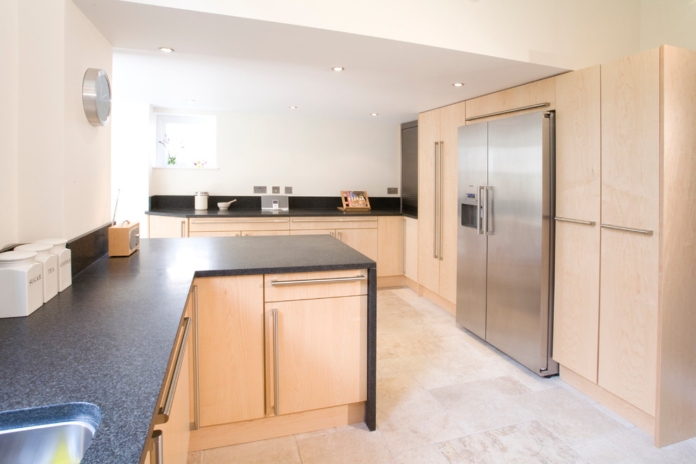 Contemporary eat-in kitchen in Other with an undermount sink, flat-panel cabinets, light wood cabinets, granite benchtops, black splashback, stone slab splashback and limestone floors.