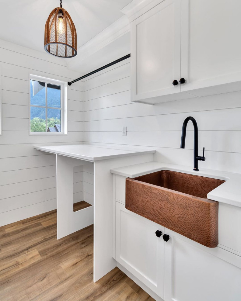 Small transitional single-wall dedicated laundry room in Vancouver with an integrated sink, flat-panel cabinets, white cabinets, quartzite benchtops, white splashback, shiplap splashback, white walls, light hardwood floors, a side-by-side washer and dryer, brown floor, white benchtop and planked wall panelling.